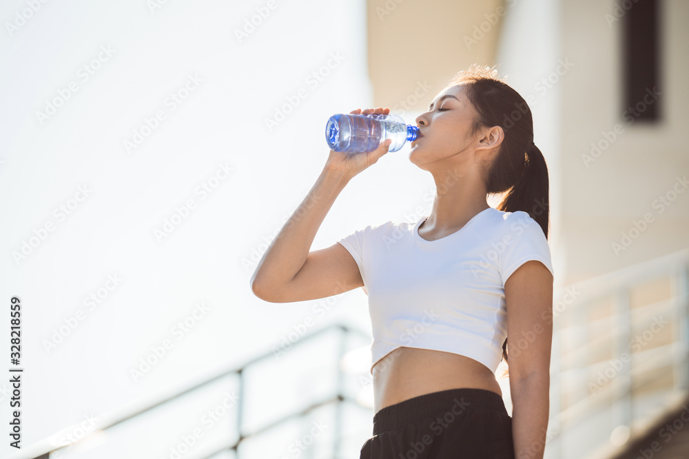 亚洲女跑步者她在喝水