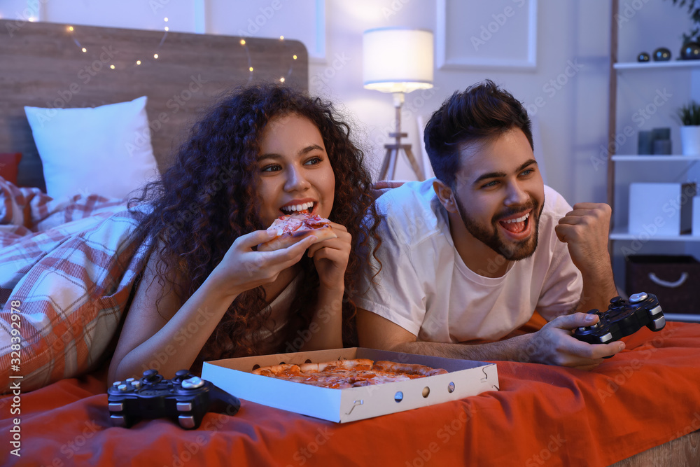 Happy young couple playing video games in bedroom