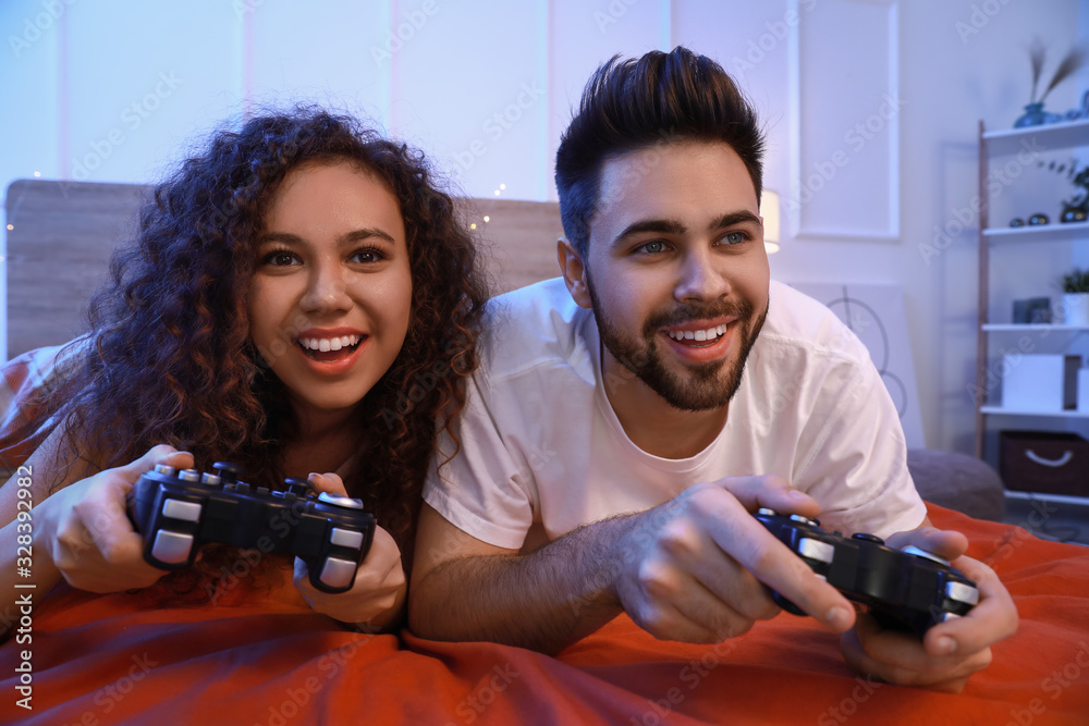 快乐的年轻情侣在卧室玩电子游戏
