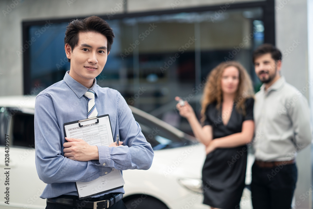 Car rental advertise concept. Asian officer male staff stands and holding rental agreement document 