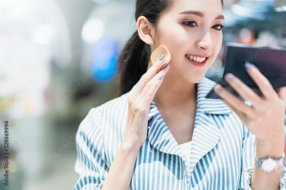 年轻迷人的亚洲女性开朗地喜欢在购物中心选择化妆品blur bokeh backgro