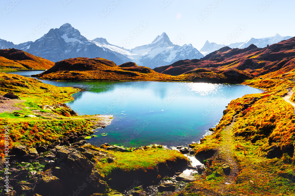 Picturesque view on Bachalpsee lake in Swiss Alps mountains. Snowy peaks of Wetterhorn, Mittelhorn a