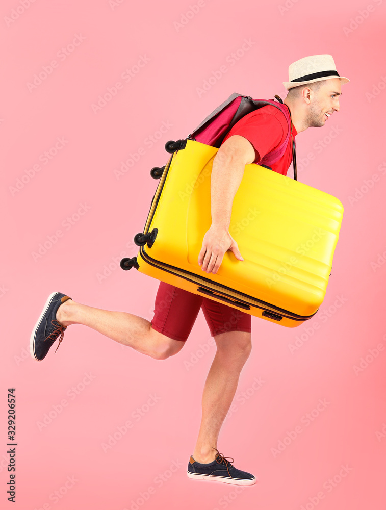 Running male tourist with luggage on color background
