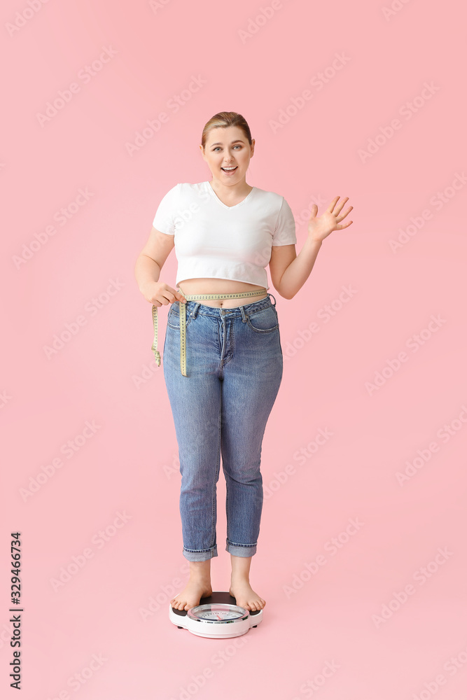 超重女性站在体重秤上，背景是彩色。减肥概念