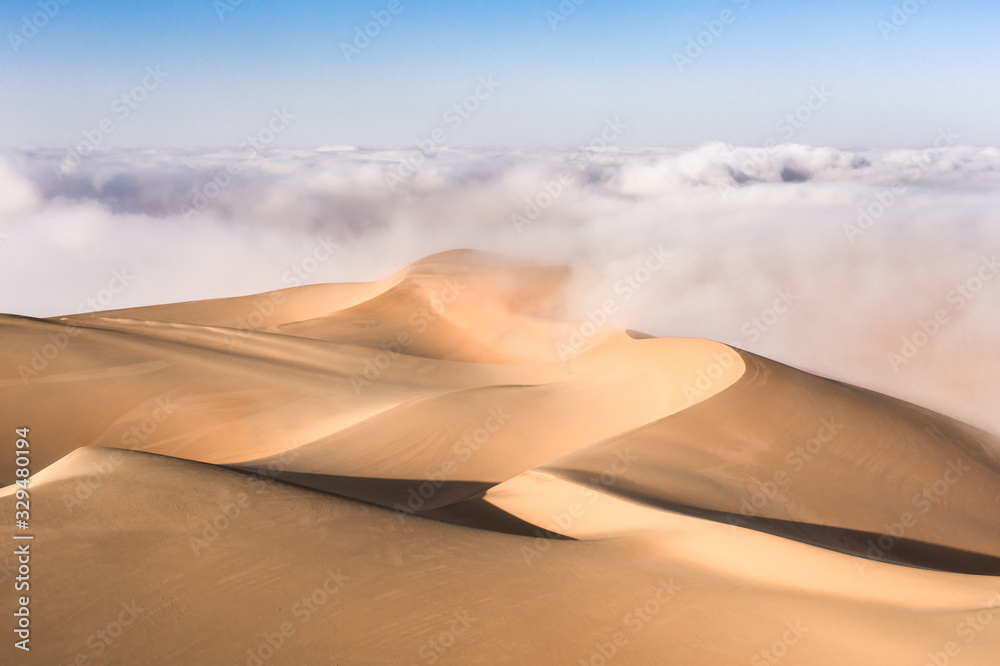 日出后，一个巨大的沙丘顶从浓雾中冒出来。阿布扎比利瓦沙漠，
