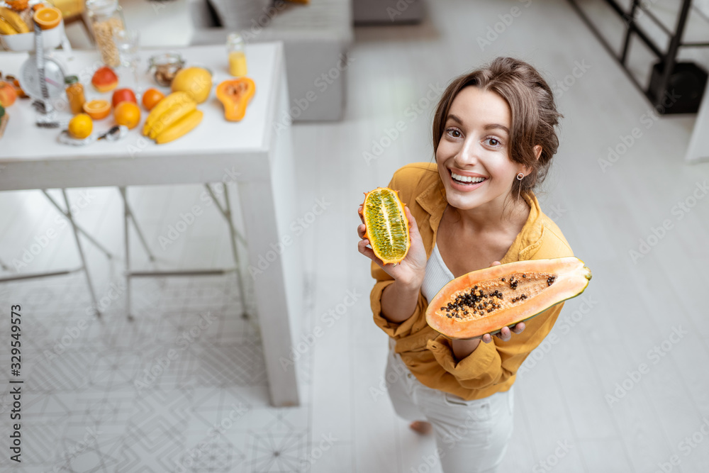 一位年轻开朗的女性的画像，家里有异国水果。幸福的概念，健康的食物