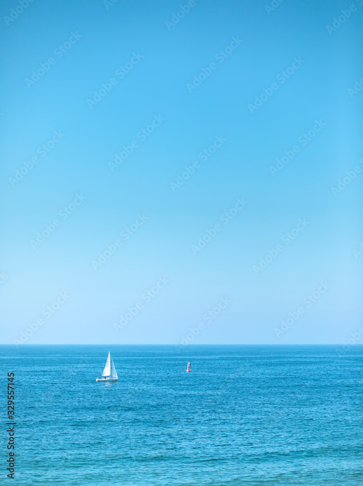 A sailboat on the azure sea under the blue sky; beautiful seascape