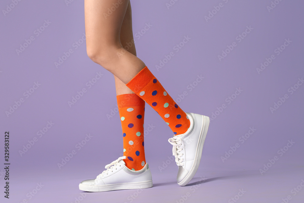 Legs of young woman in socks and shoes on color background