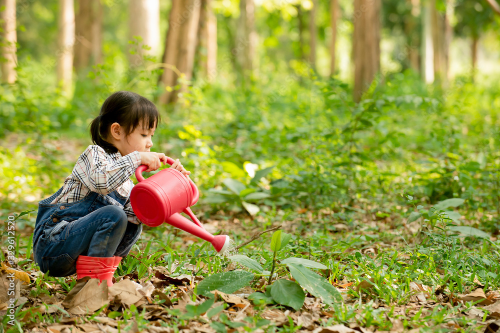Cute asian little girl  watering a tree at  park