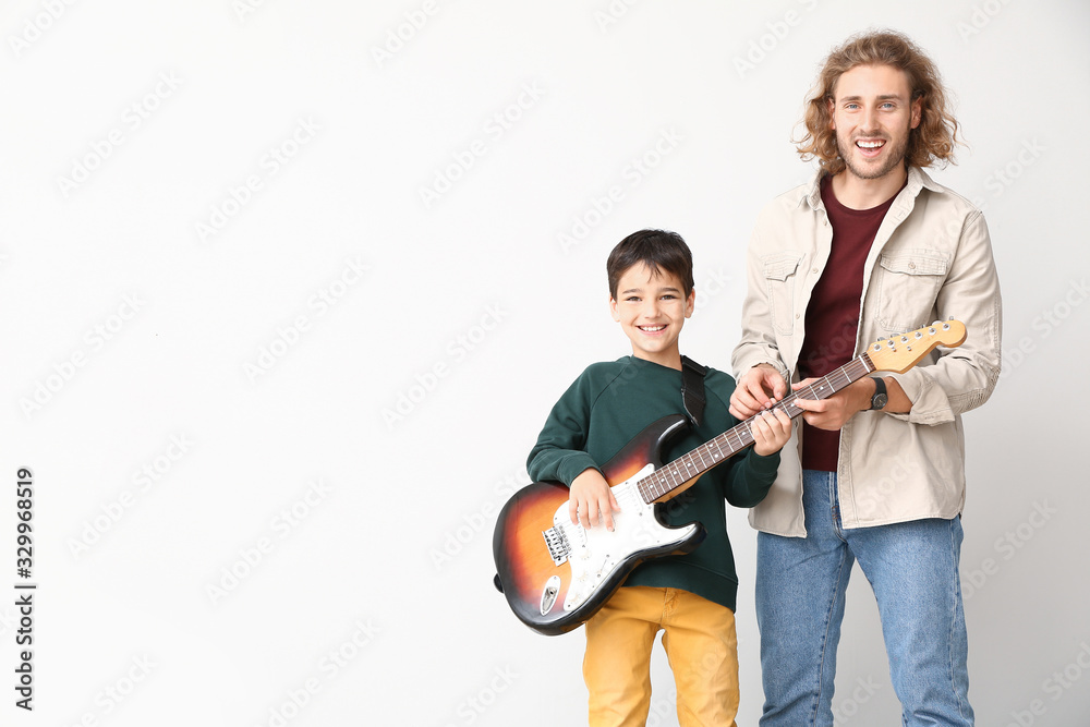一名男子在灯光背景下教儿子弹吉他
