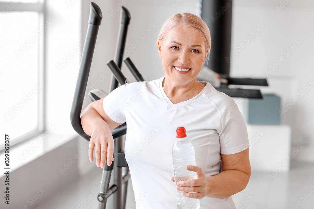 运动型成熟女性在健身房拿着一瓶水