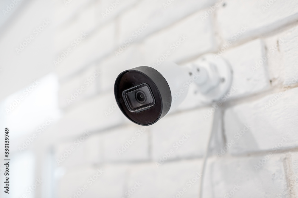 监控ip摄像头安装在室内白砖墙上。家庭视频监控概念