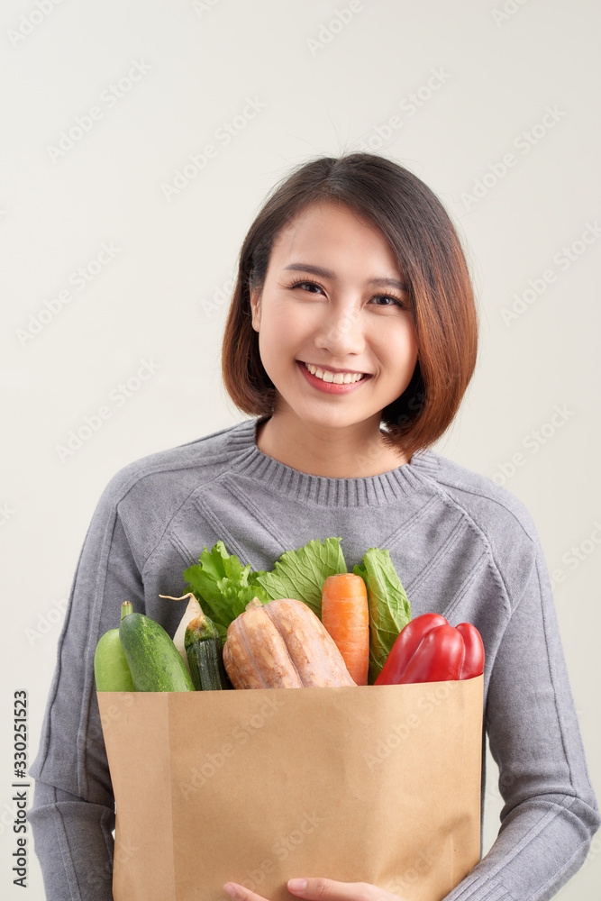 一个女人拿着装满蔬菜的纸袋的水平方向彩色图像/Adi