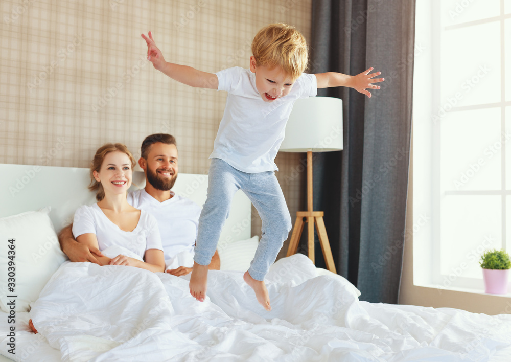 happy family mother, father and child  laughing, playing and jumping in bed    .
