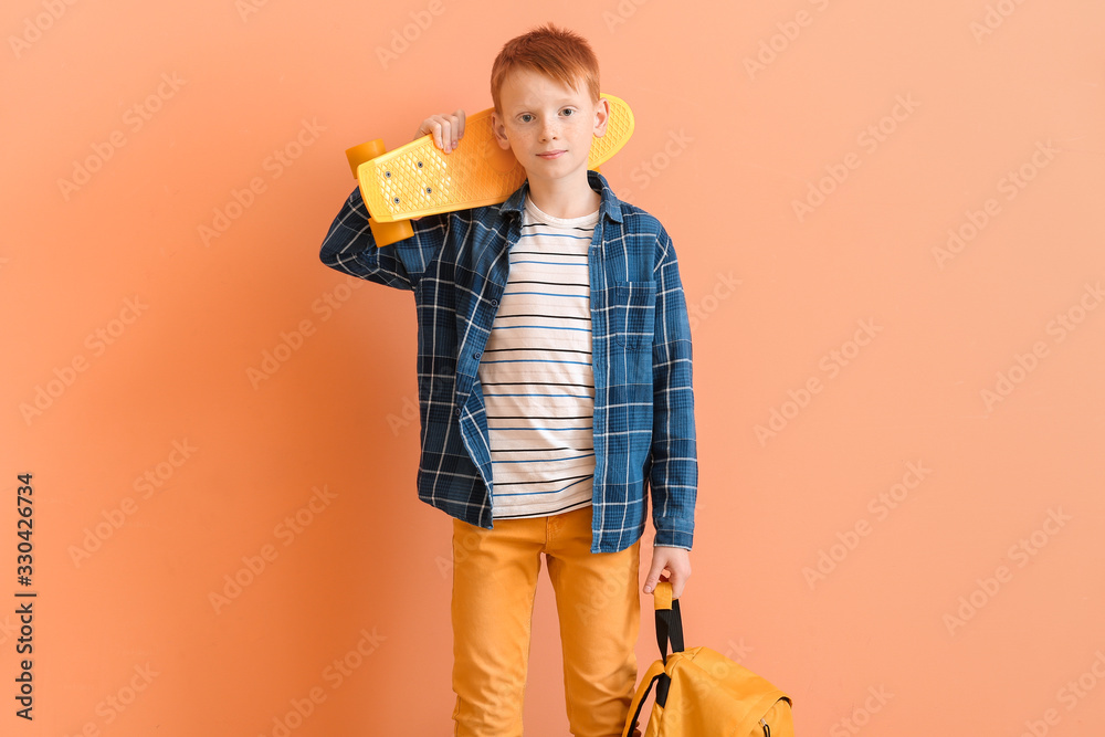 可爱的小男孩，彩色背景上有滑板和背包