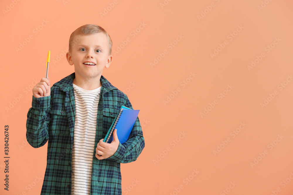 可爱的小男孩，拿着文具，在彩色背景上竖起食指