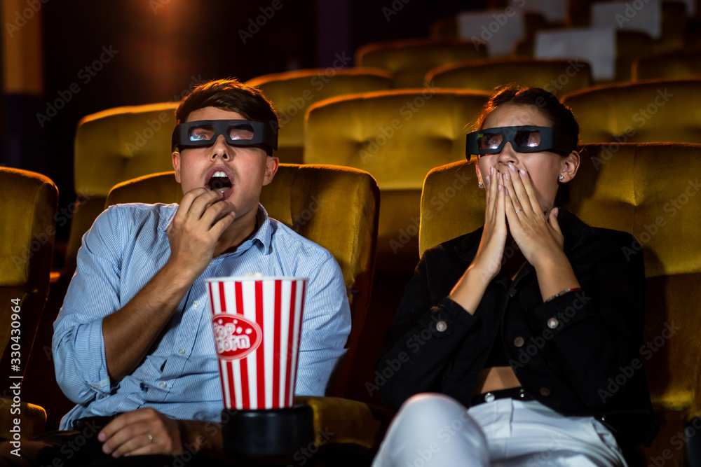 Man and woman in the cinema watching a movie with 3D glasses. with interest looking at the screen, e