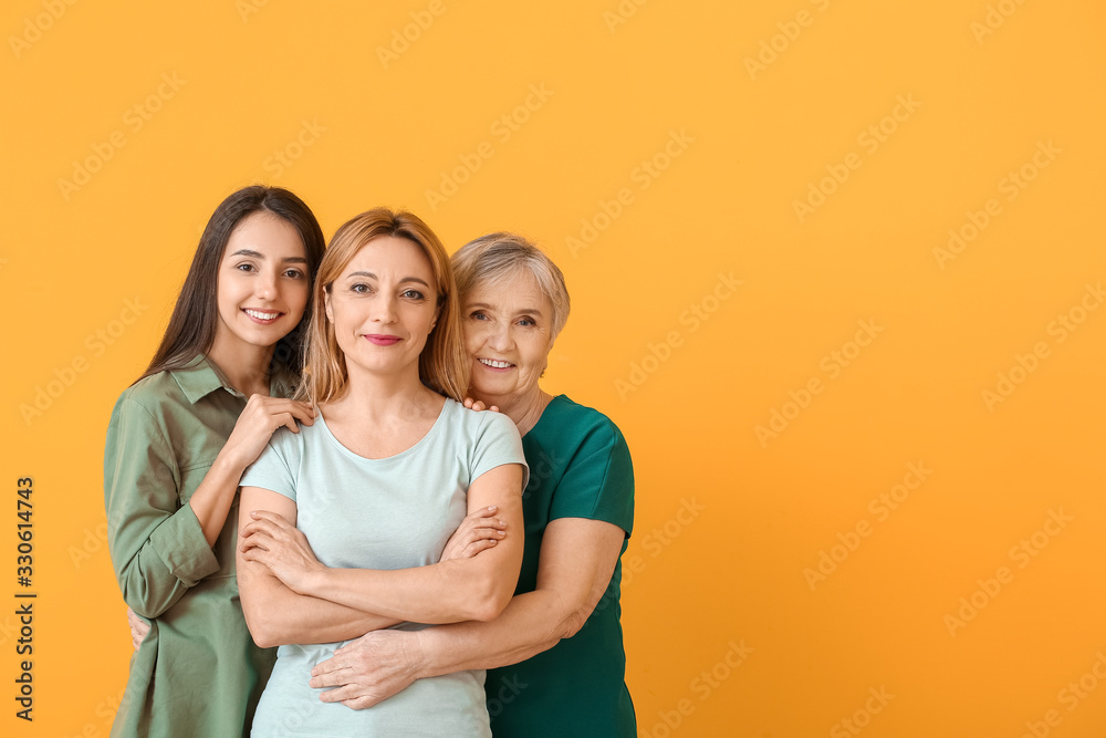 Portrait of mature woman with her adult daughter and mother on color background