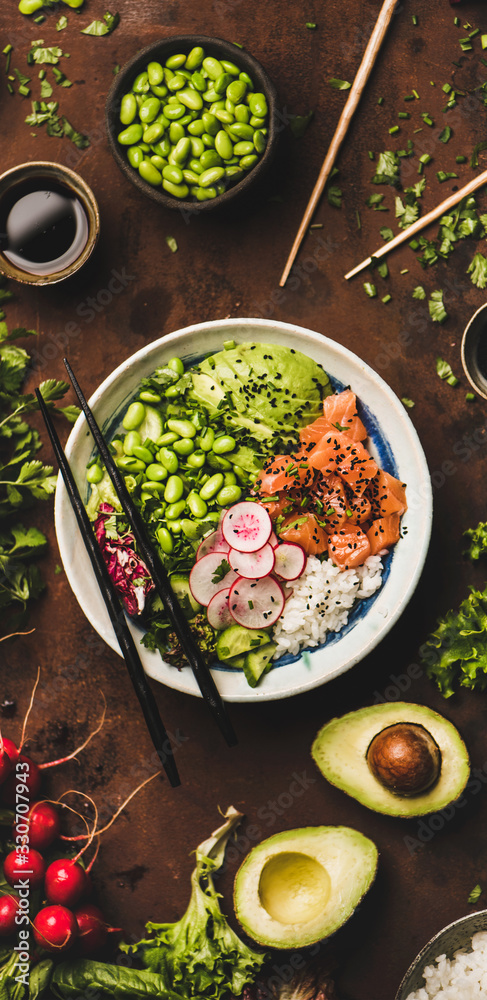 Healthy lunch. Flat-lay of salmon poke bowl or sushi bowl with various vegetables, greens, sushi ric