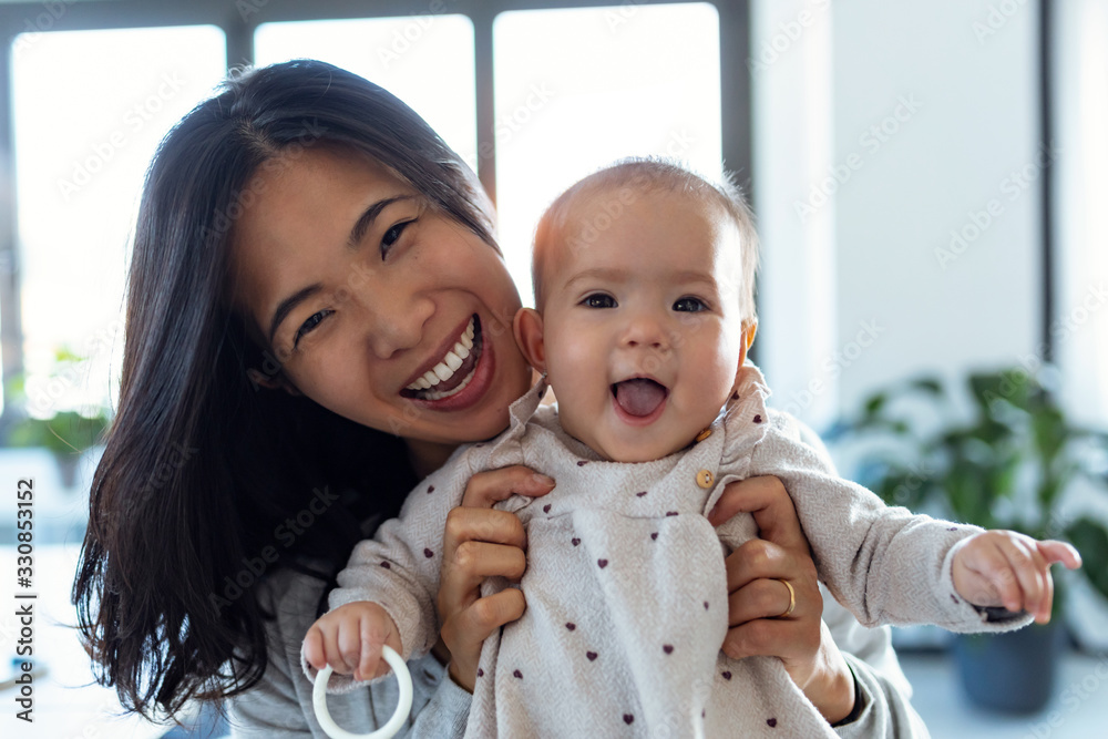快乐的年轻母亲和她的宝贝女儿呆在家里看着镜头。