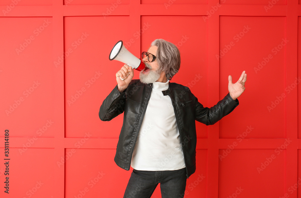 Stylish elderly man with megaphone on color background