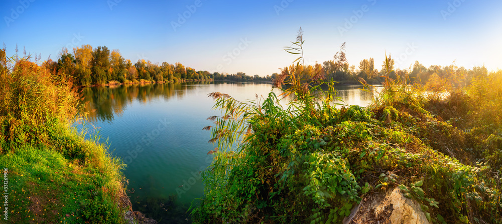 日落前，湖水清澈湛蓝，周围是树木和植被