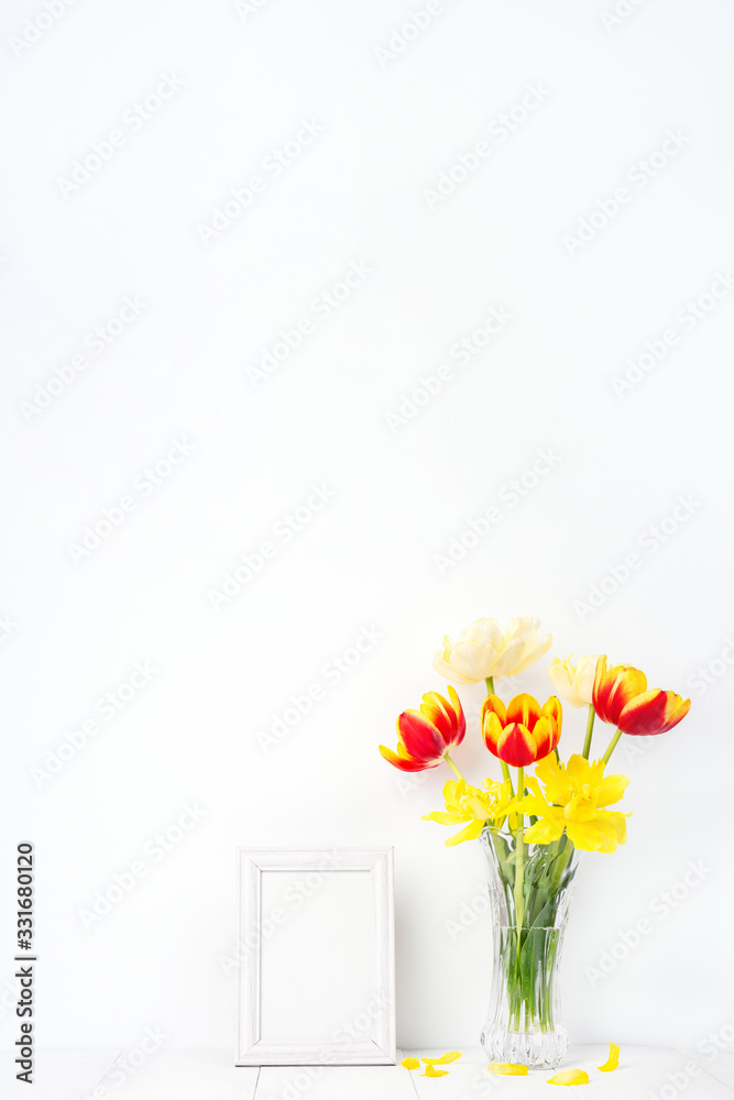 玻璃花瓶里的郁金香花，带相框，背景是干净的白色木桌