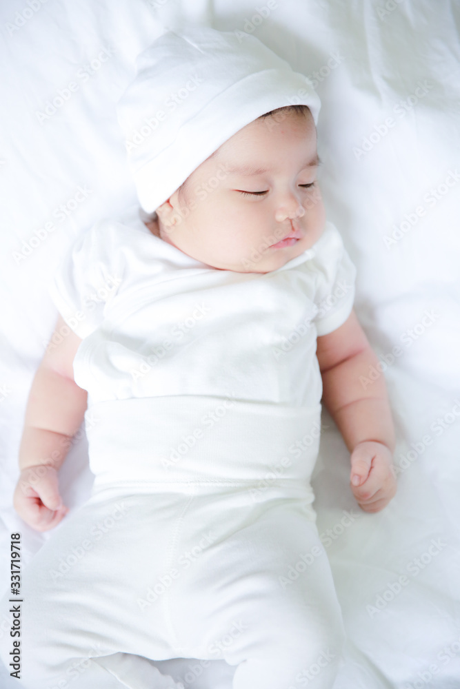 一个刚出生的亚洲孩子在白色床垫上穿着白色连衣裙的肖像