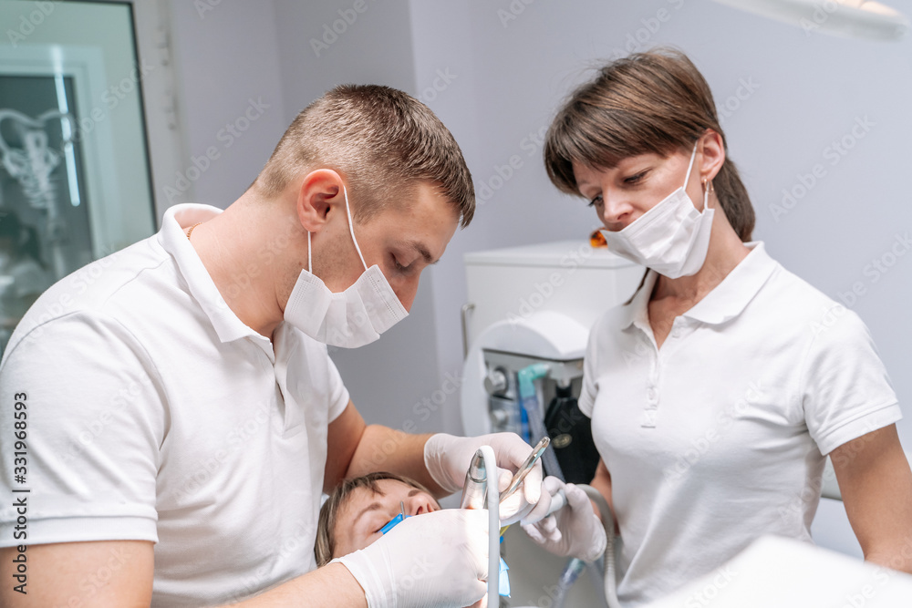 身穿制服的牙医在牙科办公室为患者进行牙科植入手术。外科手术