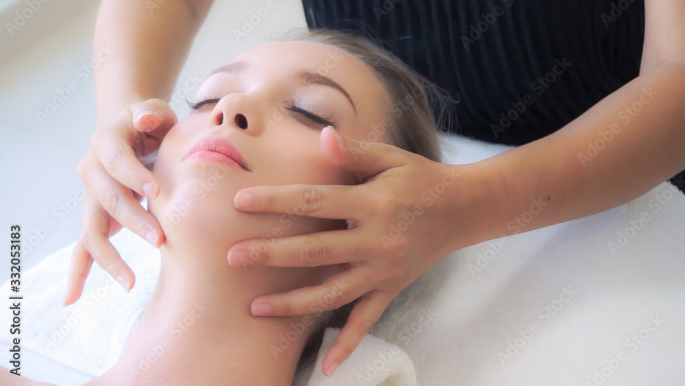 Woman gets facial and head massage in luxury spa.