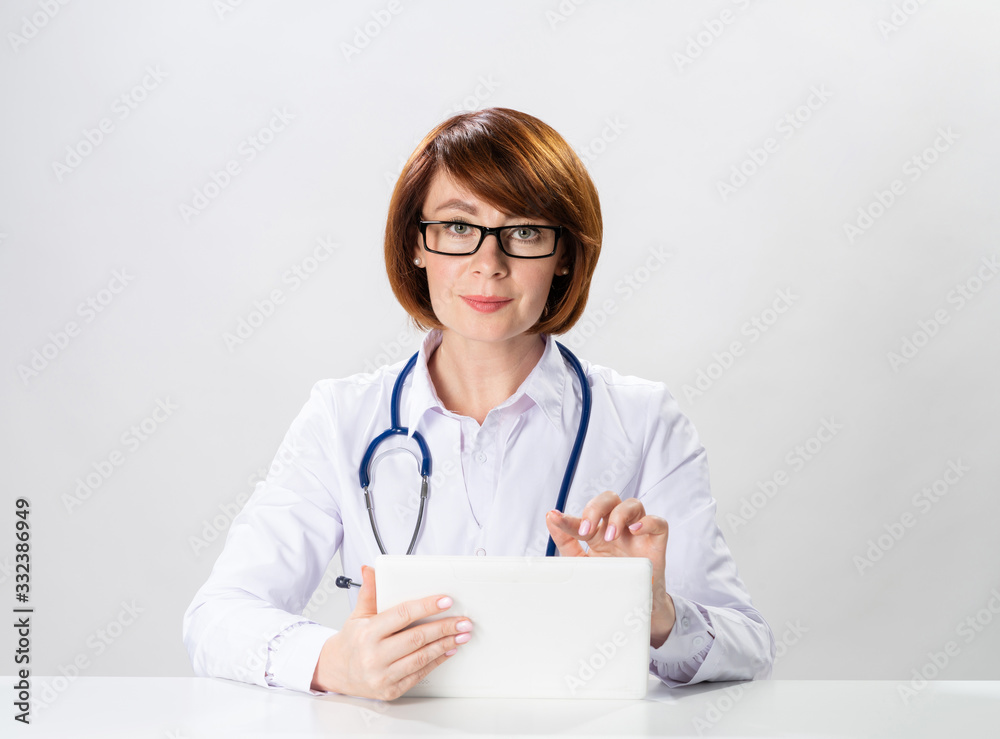 Redhead doctor using tablet computer in office