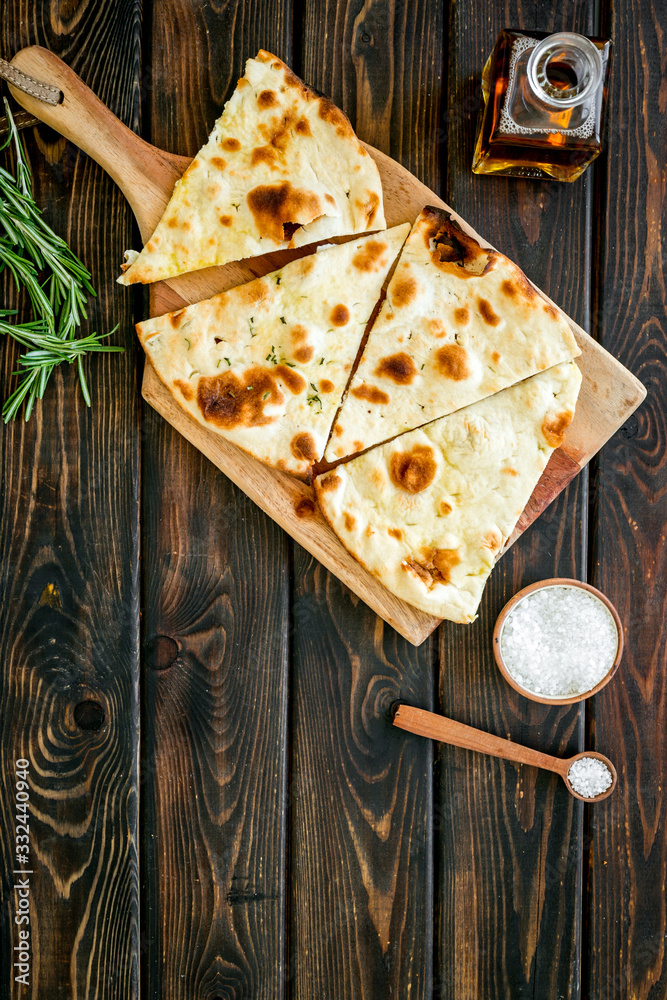 Italian focaccia with cheese and rosemary on dark wooden background top-down copy space