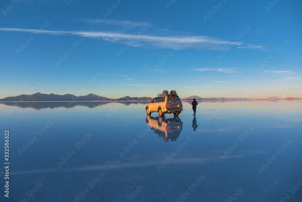 玻利维亚乌尤尼盐湖的日出被海水、汽车和人覆盖在盐碱地沙漠和天空参考