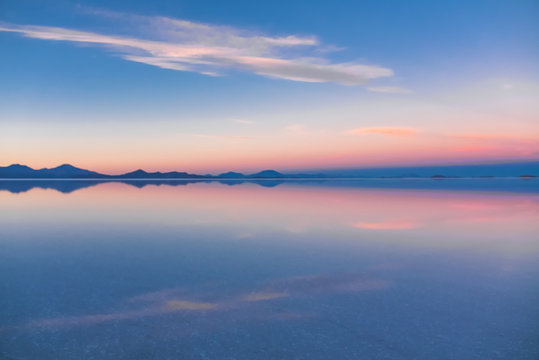 玻利维亚乌尤尼盐湖上的日出，覆盖着水、盐滩、沙漠和天空的倒影