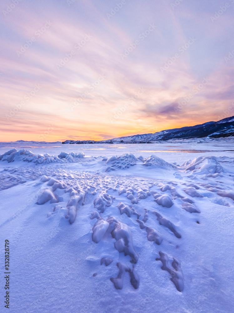 Frozen winter landscape of ice on lake Baikal during a colorful sunset. Lake Baikal, Siberia, Russia