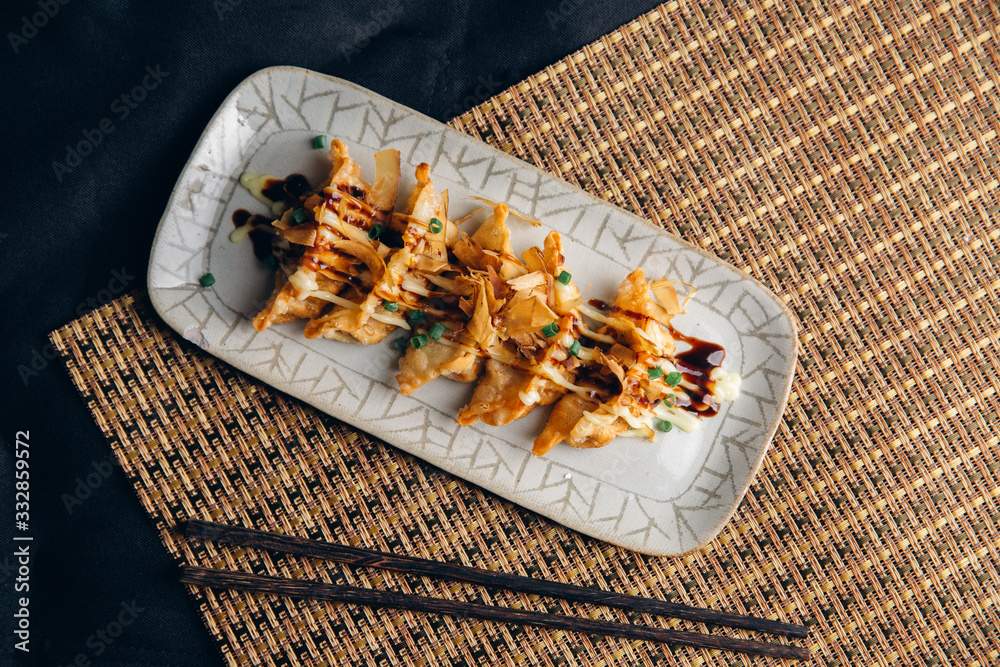 亚洲饺子Gyozas锅贴在铸铁锅上油炸，用筷子和一碗酱油食用