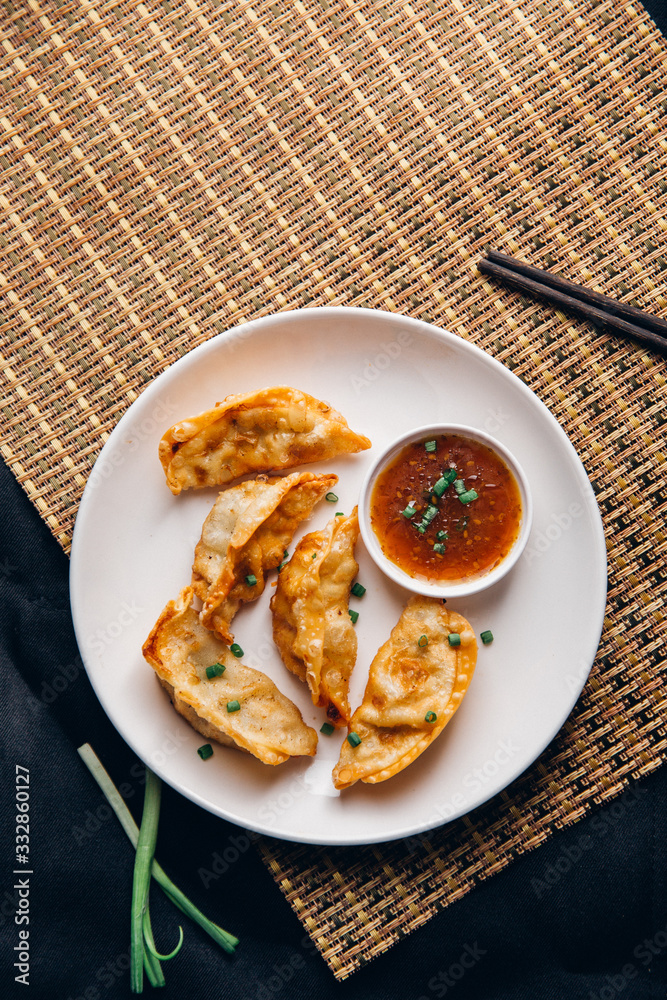 亚洲饺子Gyozas锅贴在铸铁锅上油炸，用筷子和一碗酱油食用
