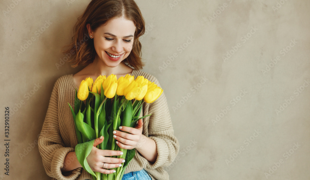 happy laughing woman with a bouquet of yellow tulips .