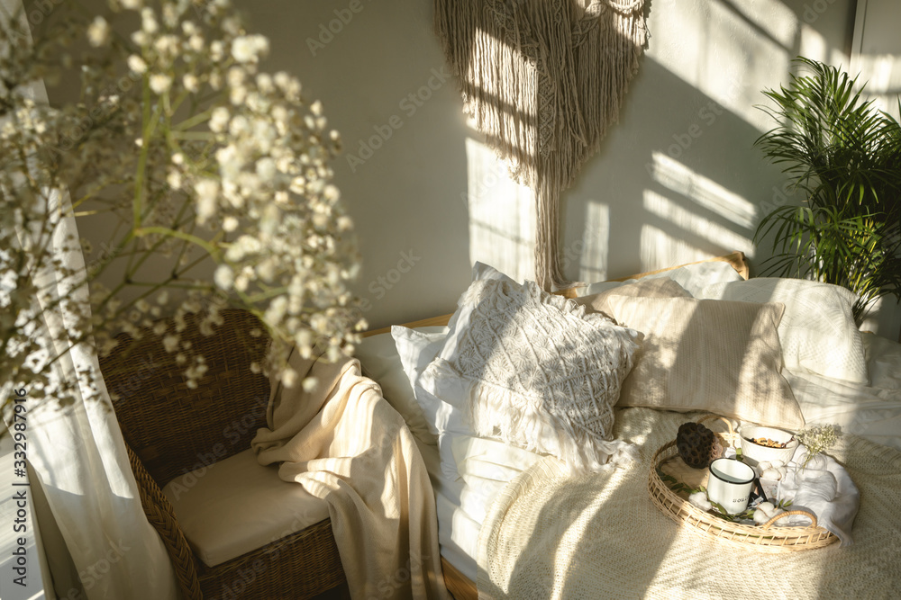 舒适的波西米亚风格阳光明媚的卧室，有灯光和阴影，白色的吉普赛花特写。Authe