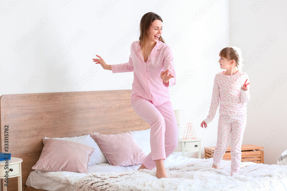 快乐的母亲和她的小女儿在卧室跳舞的早晨
