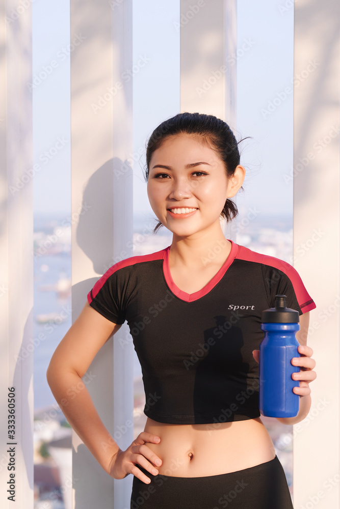 美丽的女跑步者拿着水瓶的照片。健身女性在跑步后休息