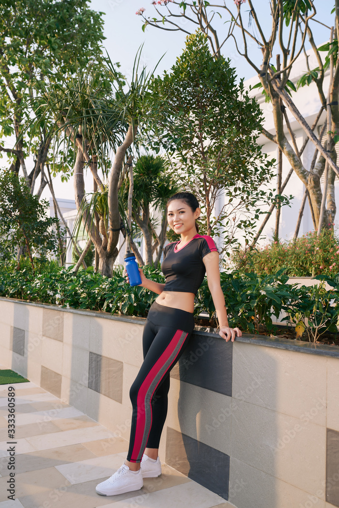 Full length shot of healthy young woman with water bottle standing in the park.