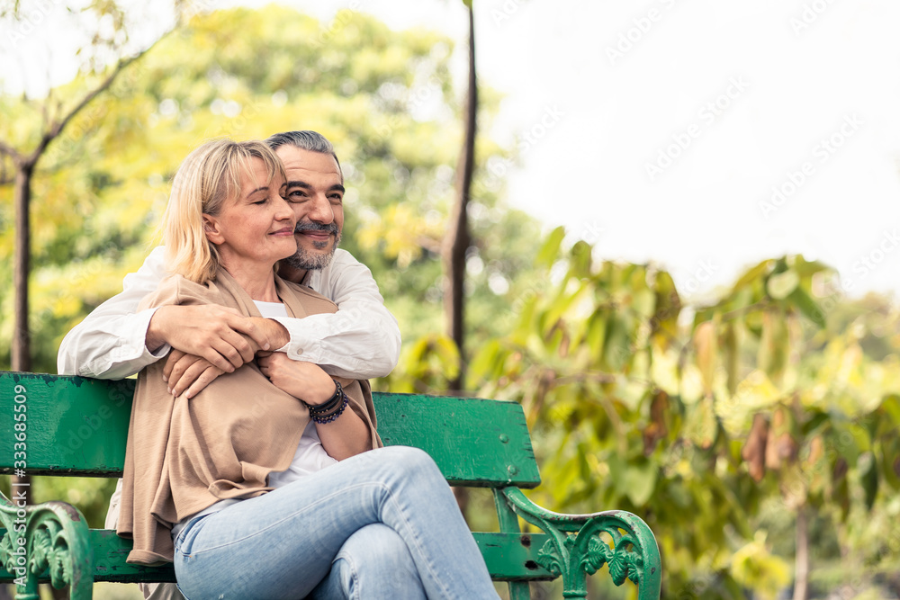 高加索老年夫妇坐在公园的长椅上。成熟的他们很快乐，享受缓慢的生活。老m