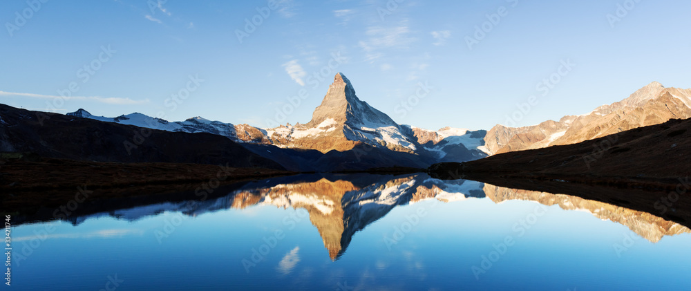 Picturesque landscape with colorful sunrise on Stellisee lake. Snowy Matterhorn Cervino peak with re