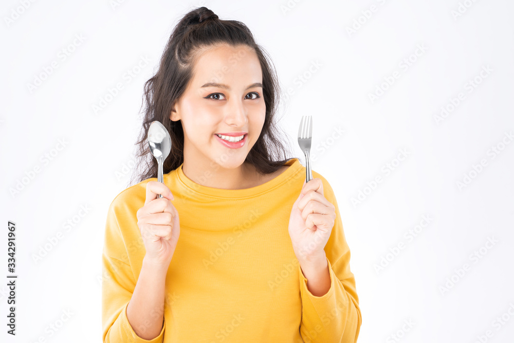Young beauty Asian woman showing spoon and fork prepare to eat food and she wearing a yellow sweater