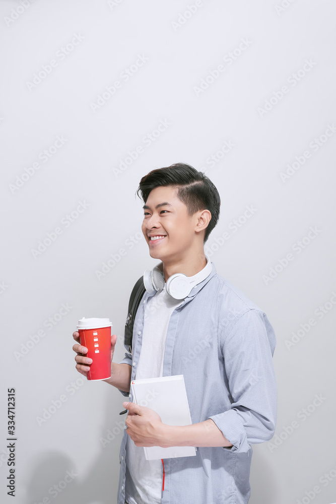 年轻英俊的男人，背着背包，手里拿着智能手机，咖啡被隔离在白底上。微笑