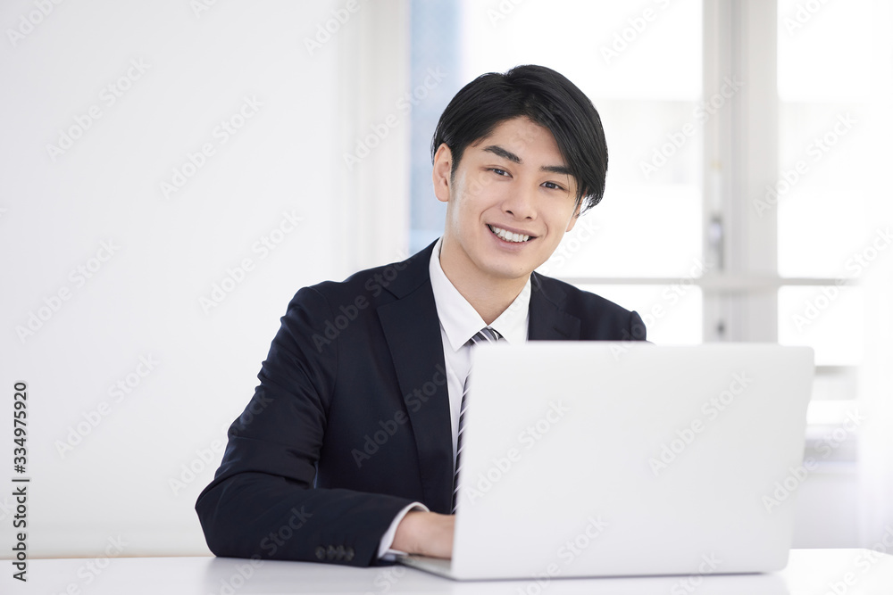 笑顔で自宅でスーツを着てテレワークをする日本人男性ビジネスマン
