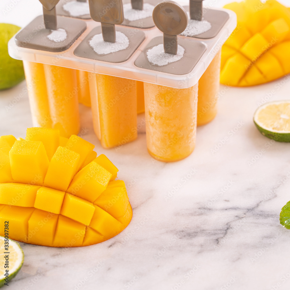 芒果冰棍，水果冰放在明亮的大理石桌子上的塑料成型盒子里。夏季茶点conc