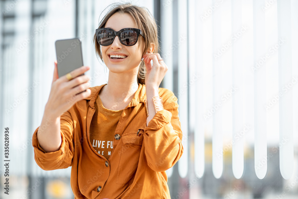 一名年轻女子坐在户外交通站用手机进行视频通话。在线