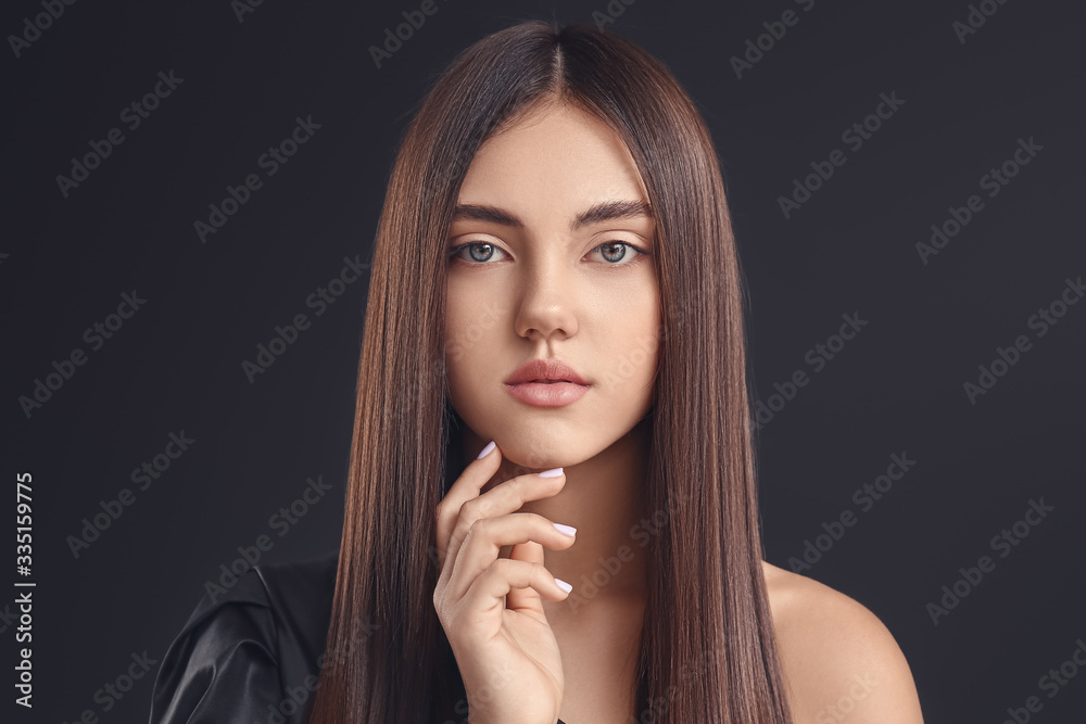 Young woman with beautiful straight hair on dark background
